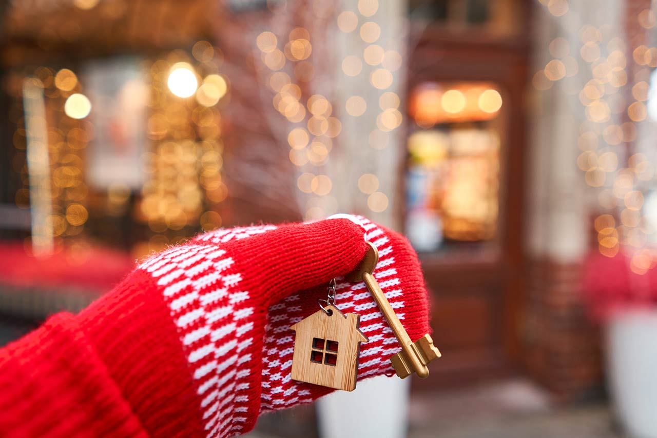 Hand in red mitten holding key with house shaped keychain