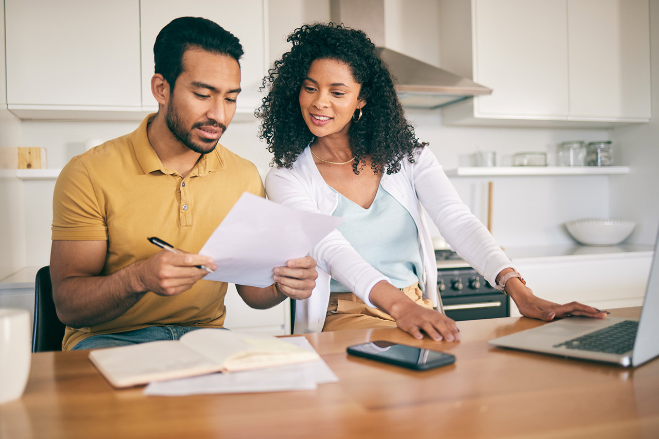 Couple reviewing financial documents at a kitchen counter